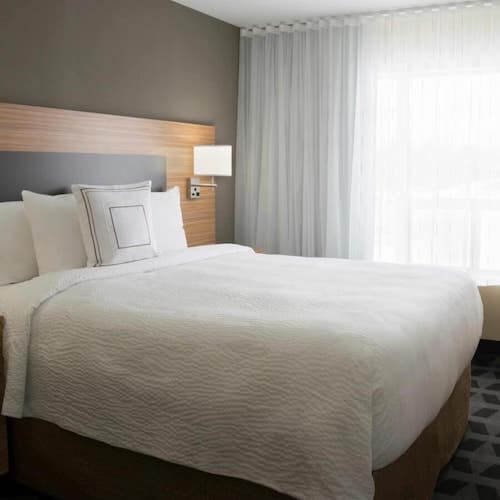 Hotel guest room with bed in front of white sheer curtains Toronto